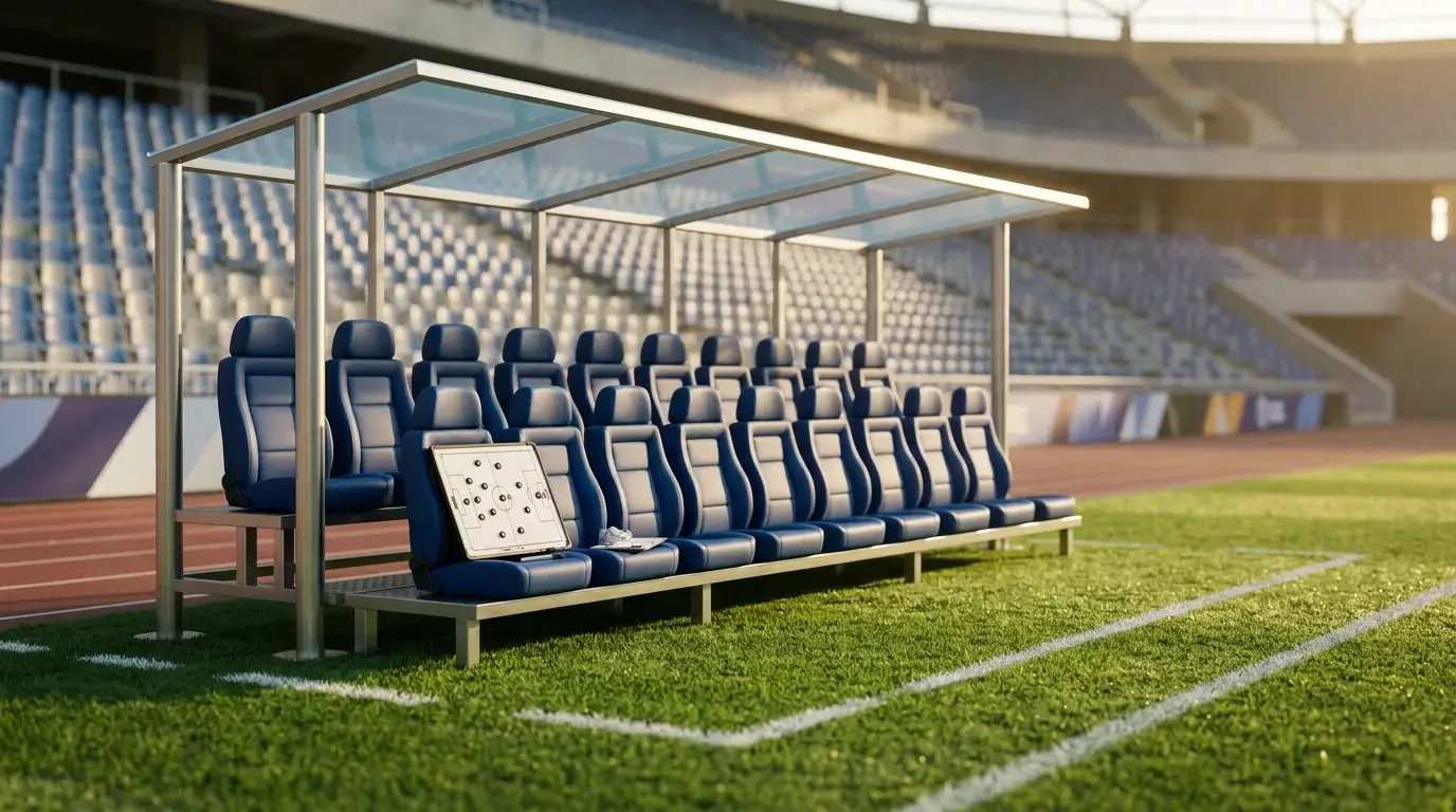Banquillo de un campo de futbol profesional con cesped verde y zona tecnica vacia antes de un partido europeo